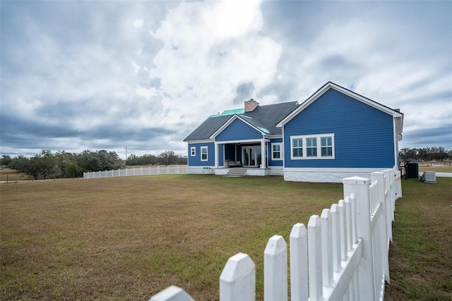 view of front of house with central AC and a front yard