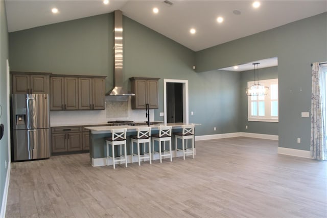 2437 Bay Lake Loop, Groveland, FL 34736 - kitchen featuring stainless steel fridge, a kitchen island with sink, high vaulted ceiling, wall chimney exhaust hood, and light wood-type flooring