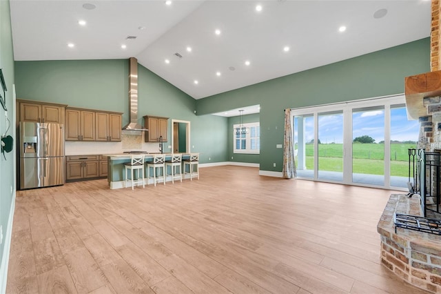 2437 Bay Lake Loop, Groveland, FL 34736 - kitchen with stainless steel fridge with ice dispenser, high vaulted ceiling, wall chimney exhaust hood, light wood-style flooring, and a breakfast bar