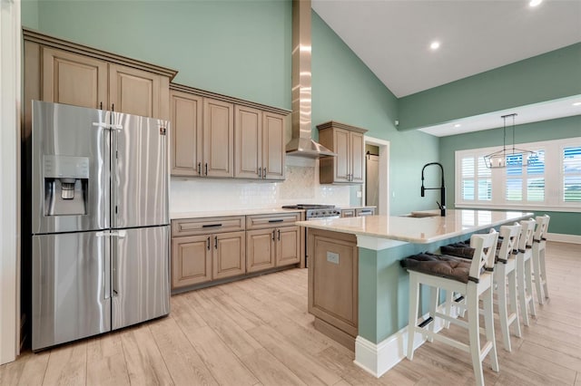 2437 Bay Lake Loop, Groveland, FL 34736 - kitchen with stainless steel fridge, wall chimney exhaust hood, backsplash, light wood-style flooring, and a center island with sink