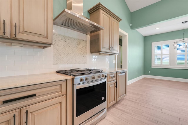 2437 Bay Lake Loop, Groveland, FL 34736 - kitchen with stainless steel gas range, wall chimney range hood, light wood-style flooring, tasteful backsplash, and pendant lighting