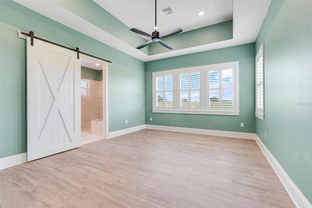 2437 Bay Lake Loop, Groveland, FL 34736 - unfurnished bedroom with a barn door, wood finished floors, a raised ceiling, connected bathroom, and recessed lighting