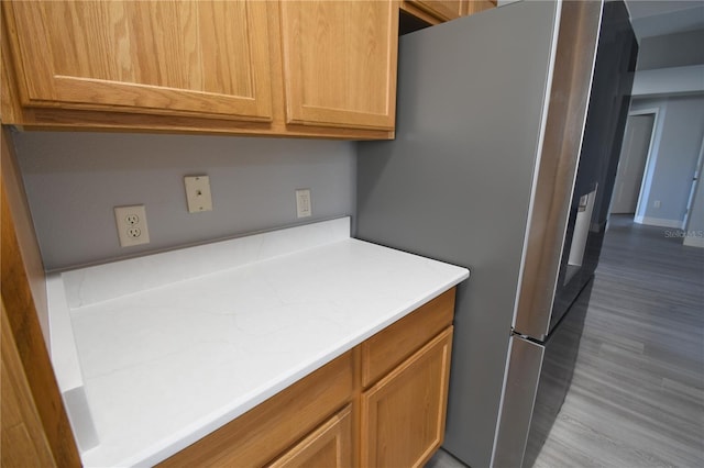 kitchen with stainless steel fridge and light hardwood / wood-style flooring