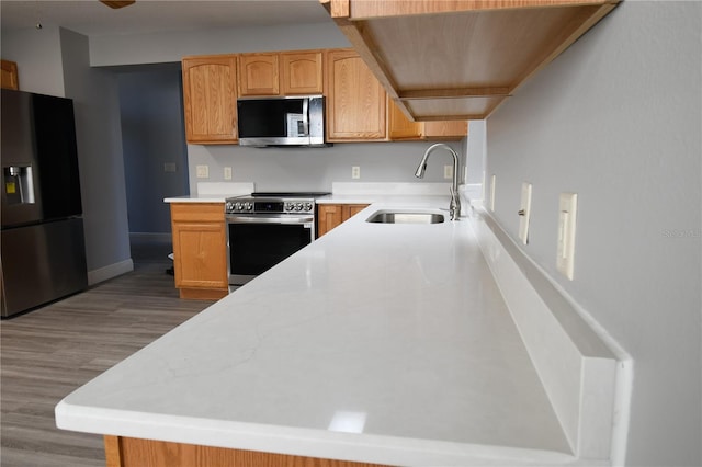 kitchen featuring sink, light hardwood / wood-style flooring, light brown cabinets, kitchen peninsula, and stainless steel appliances