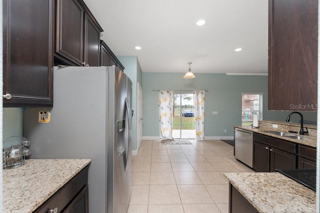 kitchen with light stone countertops, pendant lighting, stainless steel appliances, and sink