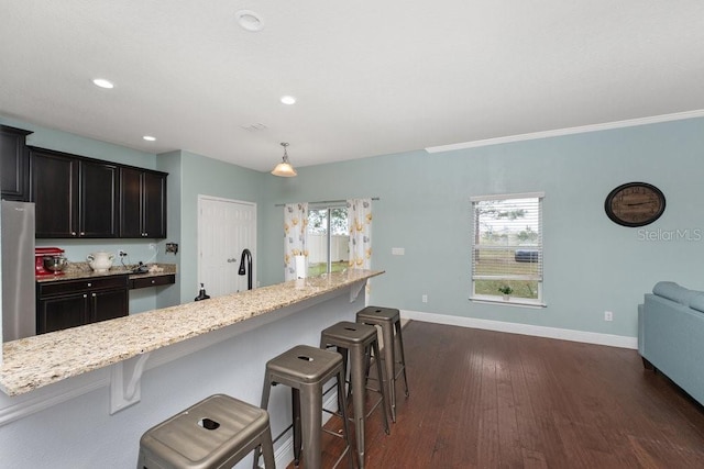 kitchen featuring dark hardwood / wood-style floors, a kitchen bar, a wealth of natural light, and stainless steel refrigerator