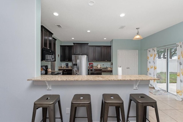 kitchen featuring light stone countertops, a kitchen breakfast bar, kitchen peninsula, light tile patterned floors, and black appliances