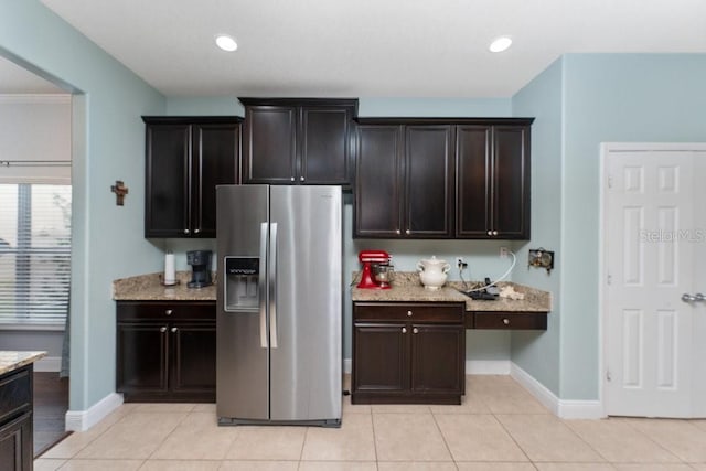 kitchen featuring light stone countertops, light tile patterned floors, and stainless steel refrigerator with ice dispenser