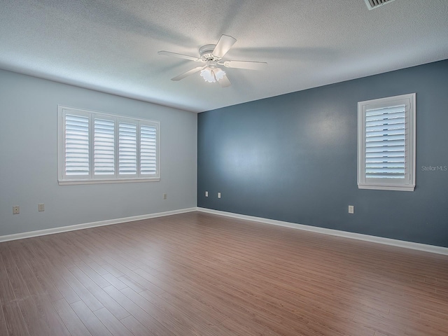 spare room with hardwood / wood-style flooring, ceiling fan, and a textured ceiling