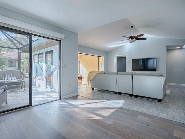 unfurnished living room featuring light wood-type flooring, vaulted ceiling, and ceiling fan