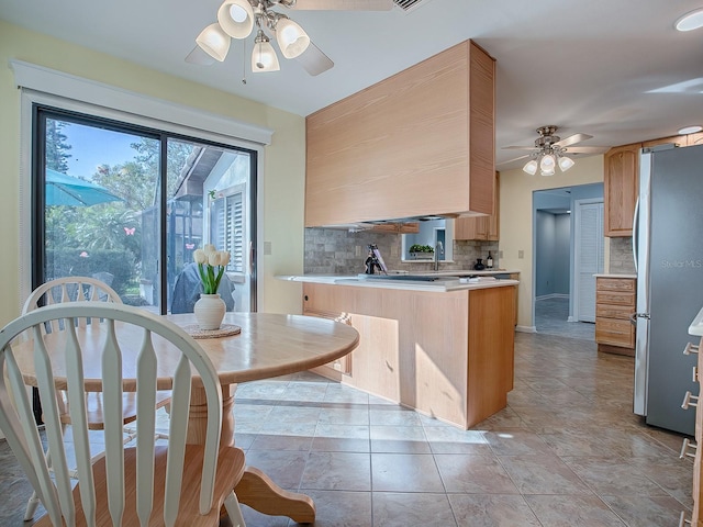 102 Cedar Way, Yalaha, FL 34797 - kitchen featuring freestanding refrigerator, ceiling fan, decorative backsplash, a peninsula, and light countertops