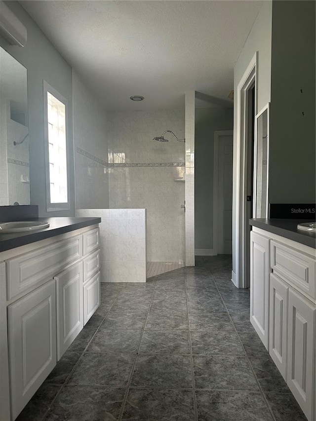 bathroom featuring an AC wall unit, a textured ceiling, vanity, and a tile shower