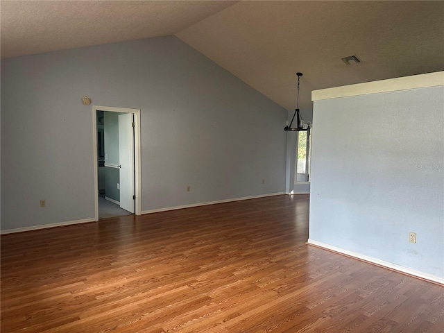 empty room with a chandelier, high vaulted ceiling, wood-type flooring, and a textured ceiling