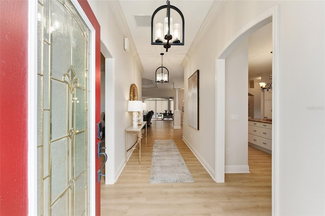 hall featuring crown molding, light hardwood / wood-style flooring, and an inviting chandelier