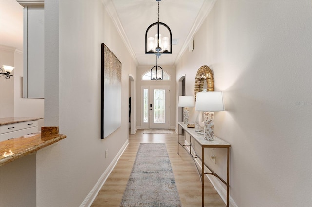 doorway to outside featuring an inviting chandelier, light hardwood / wood-style flooring, and ornamental molding