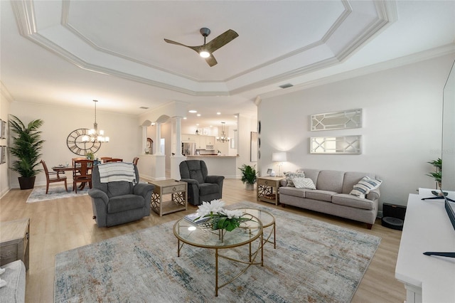 living room featuring ceiling fan with notable chandelier, light hardwood / wood-style floors, and crown molding