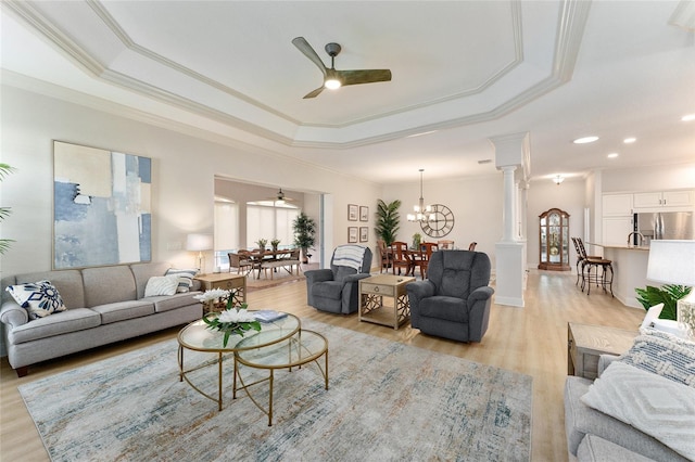 living room with ornate columns, light hardwood / wood-style flooring, ceiling fan with notable chandelier, and ornamental molding