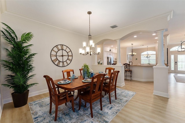 dining area featuring ornate columns, crown molding, light hardwood / wood-style flooring, and a notable chandelier