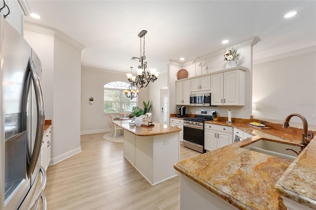 kitchen featuring sink, light hardwood / wood-style flooring, appliances with stainless steel finishes, a notable chandelier, and a kitchen island