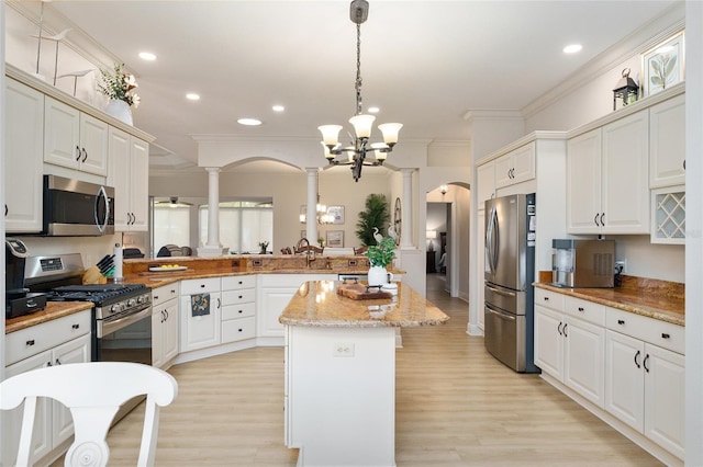 kitchen with a center island, light wood-type flooring, hanging light fixtures, and appliances with stainless steel finishes