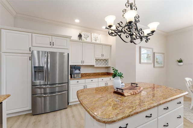 kitchen with light wood-type flooring, ornamental molding, stainless steel fridge with ice dispenser, a center island, and white cabinetry