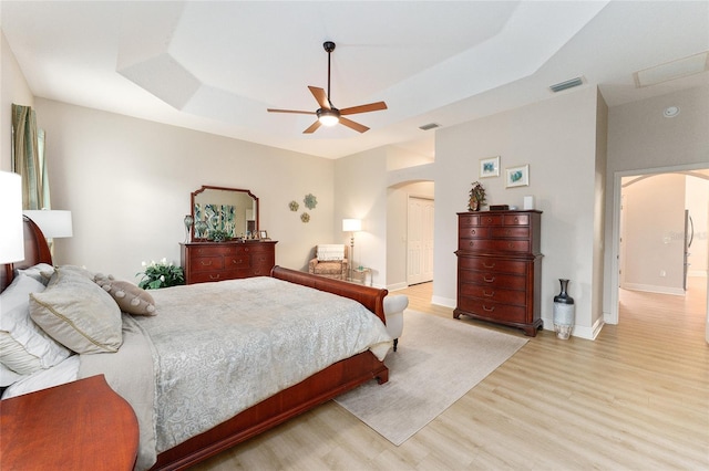 bedroom with a tray ceiling, ceiling fan, and light hardwood / wood-style floors