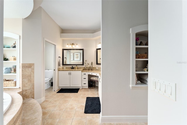 bathroom with built in features, tile patterned floors, tiled bath, toilet, and vanity