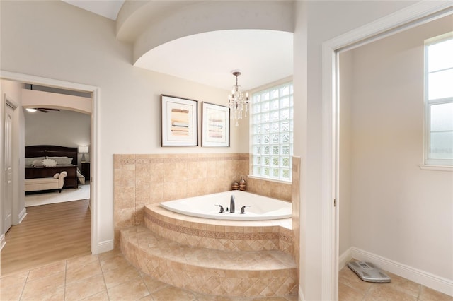 bathroom featuring tile patterned floors, tiled bath, and a chandelier