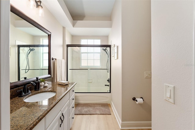 bathroom featuring wood-type flooring, vanity, and enclosed tub / shower combo