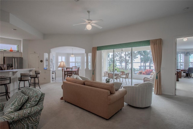 living room featuring ceiling fan, light colored carpet, plenty of natural light, and ornate columns