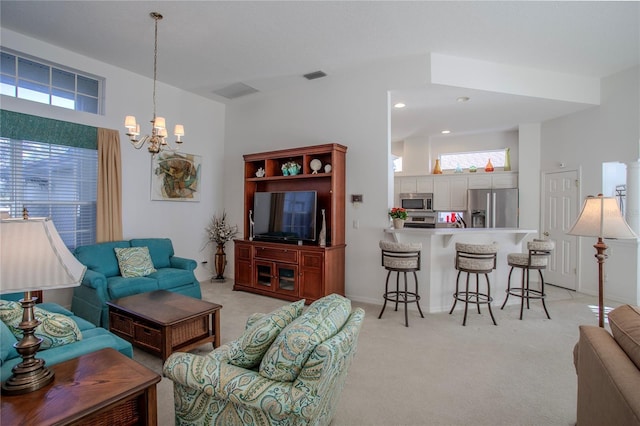 carpeted living room with a high ceiling, plenty of natural light, and a chandelier