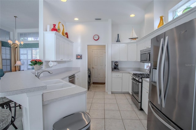 kitchen with kitchen peninsula, appliances with stainless steel finishes, sink, and white cabinetry