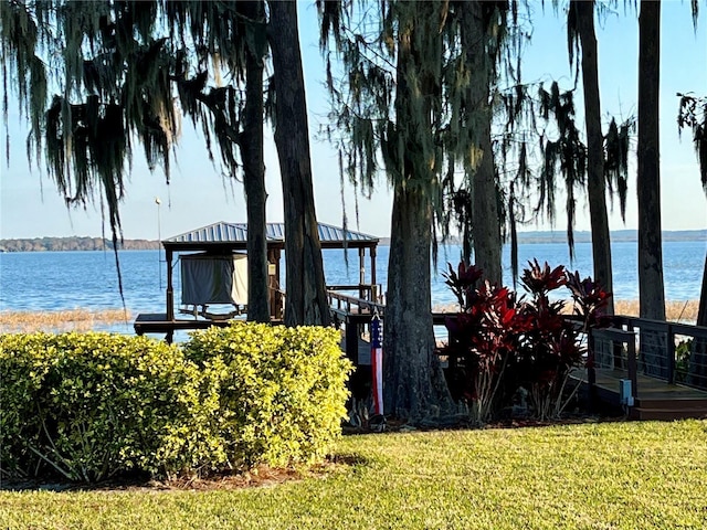 view of dock with a gazebo, a water view, and a lawn