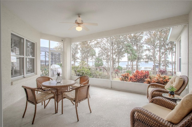 sunroom featuring ceiling fan and a water view