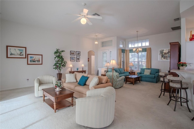 living room with ceiling fan with notable chandelier and light colored carpet