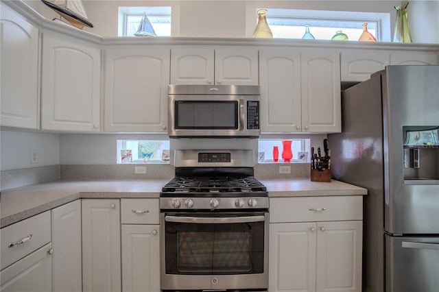 kitchen with a wealth of natural light, appliances with stainless steel finishes, and white cabinets