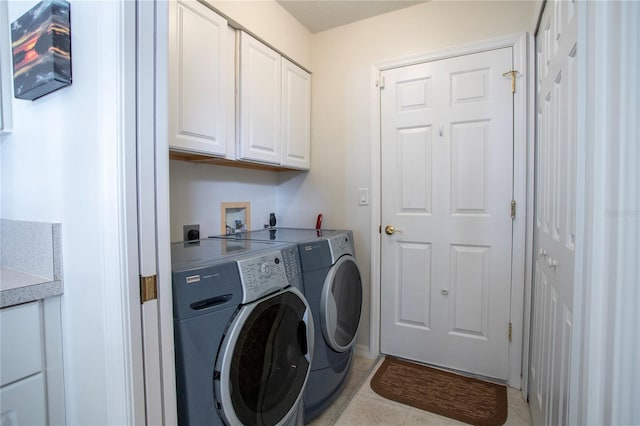 laundry area featuring cabinets, light tile patterned flooring, and washing machine and clothes dryer