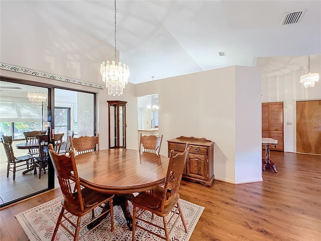 dining area featuring light hardwood / wood-style floors, high vaulted ceiling, and an inviting chandelier