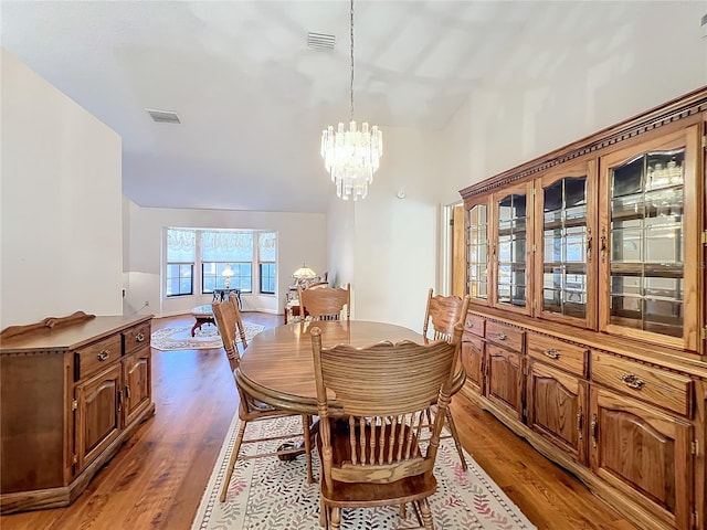 dining space with hardwood / wood-style floors and an inviting chandelier