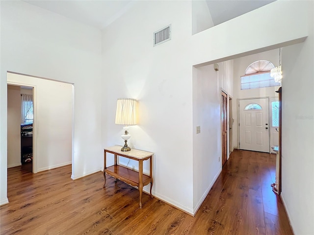 entrance foyer with an inviting chandelier, high vaulted ceiling, and hardwood / wood-style flooring