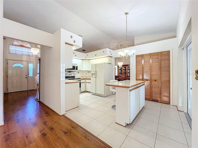 kitchen featuring a center island, lofted ceiling, light hardwood / wood-style flooring, appliances with stainless steel finishes, and a notable chandelier