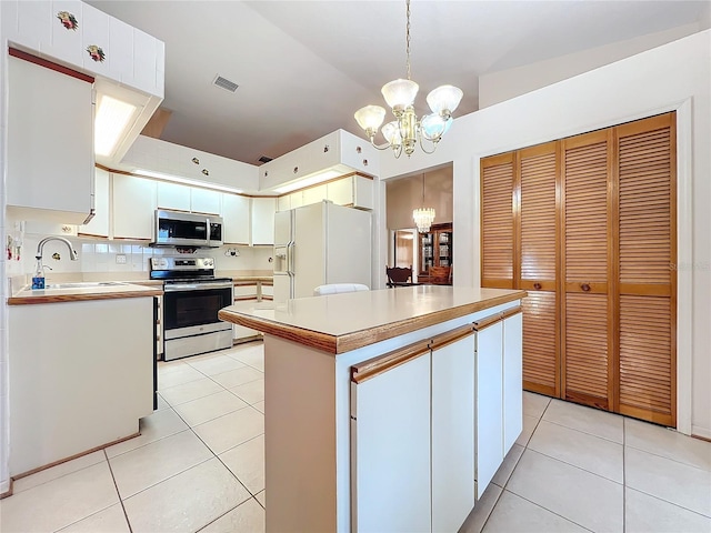 kitchen featuring stainless steel appliances, decorative light fixtures, an inviting chandelier, white cabinets, and a center island