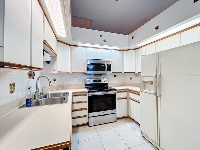 kitchen featuring sink, decorative backsplash, appliances with stainless steel finishes, light tile patterned flooring, and white cabinetry