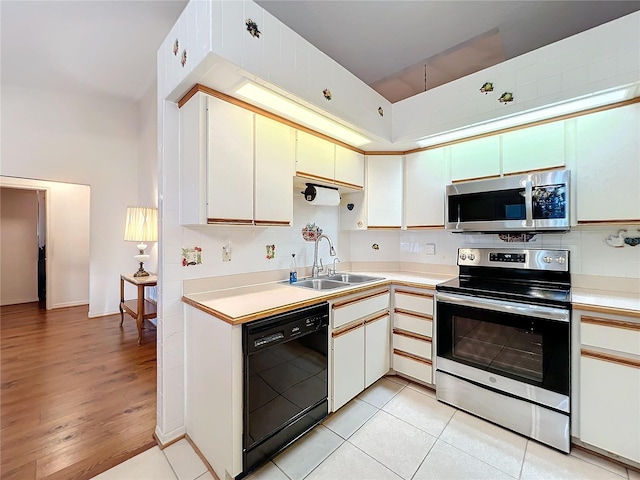 kitchen featuring sink, white cabinetry, stainless steel appliances, and light hardwood / wood-style flooring