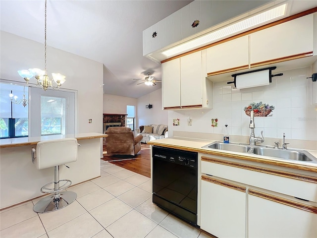 kitchen featuring a wealth of natural light, hanging light fixtures, light wood-type flooring, and black dishwasher