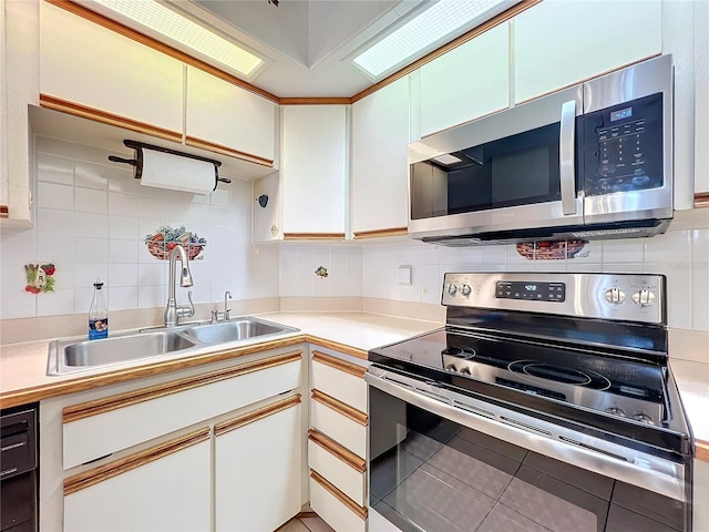 kitchen with tasteful backsplash, white cabinets, and stainless steel appliances