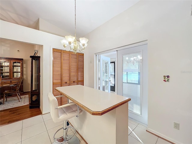 kitchen featuring a breakfast bar area, light tile patterned floors, pendant lighting, and lofted ceiling