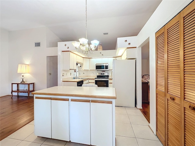 kitchen featuring white cabinetry, sink, stainless steel appliances, decorative light fixtures, and light tile patterned flooring