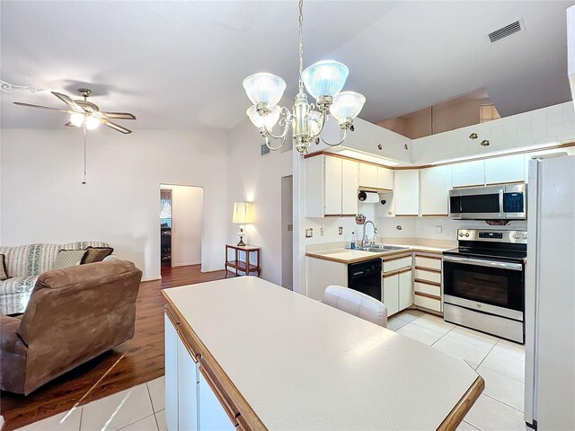 kitchen featuring appliances with stainless steel finishes, ceiling fan with notable chandelier, light tile patterned floors, white cabinetry, and hanging light fixtures