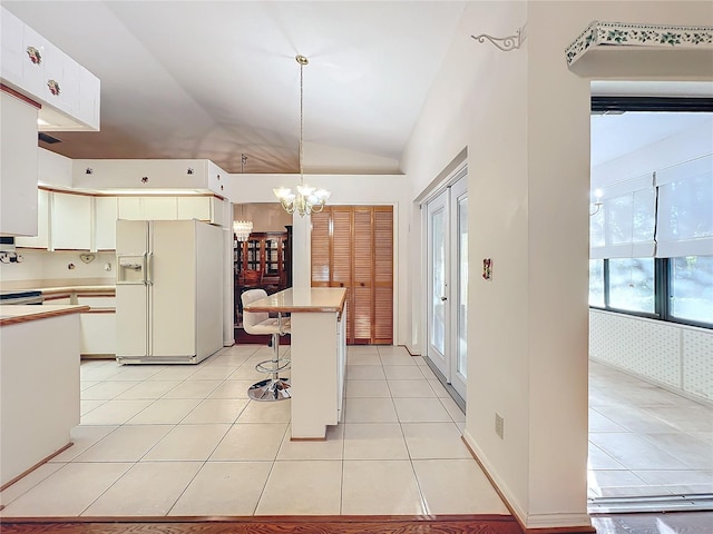 kitchen featuring hanging light fixtures, white refrigerator with ice dispenser, vaulted ceiling, a breakfast bar, and light tile patterned flooring